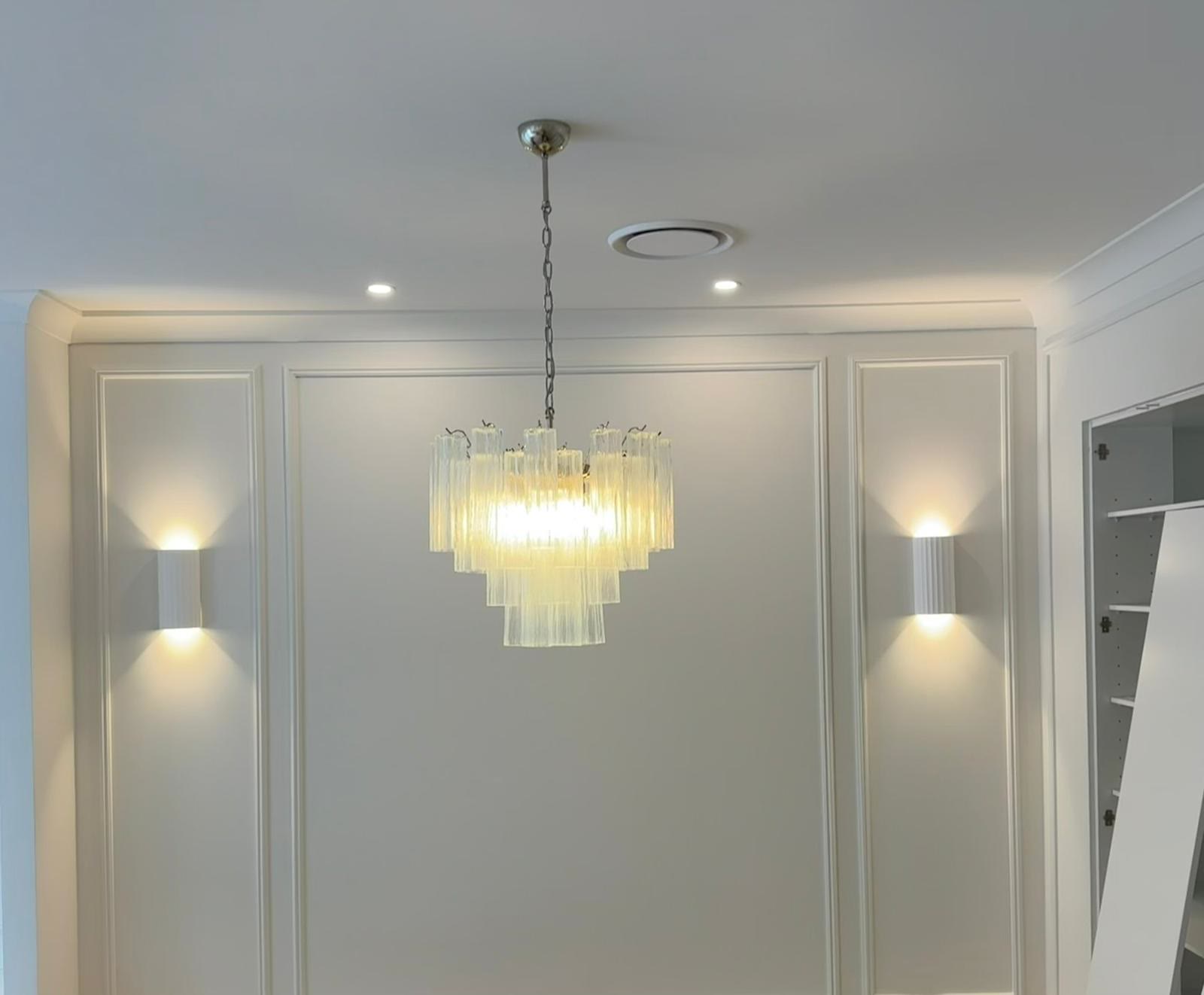 Pendant chandelier with wall sconces on a panelled wall