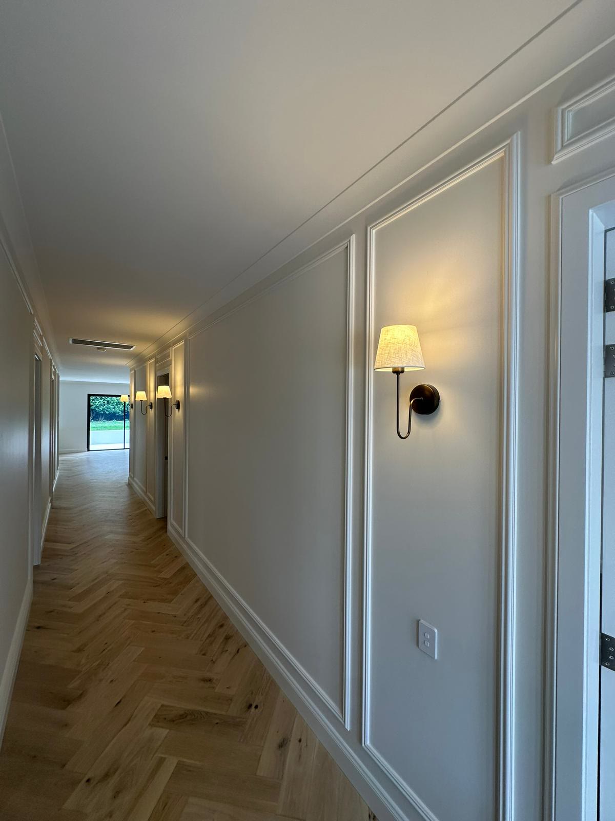 Hallway with wall sconces and herringbone floor