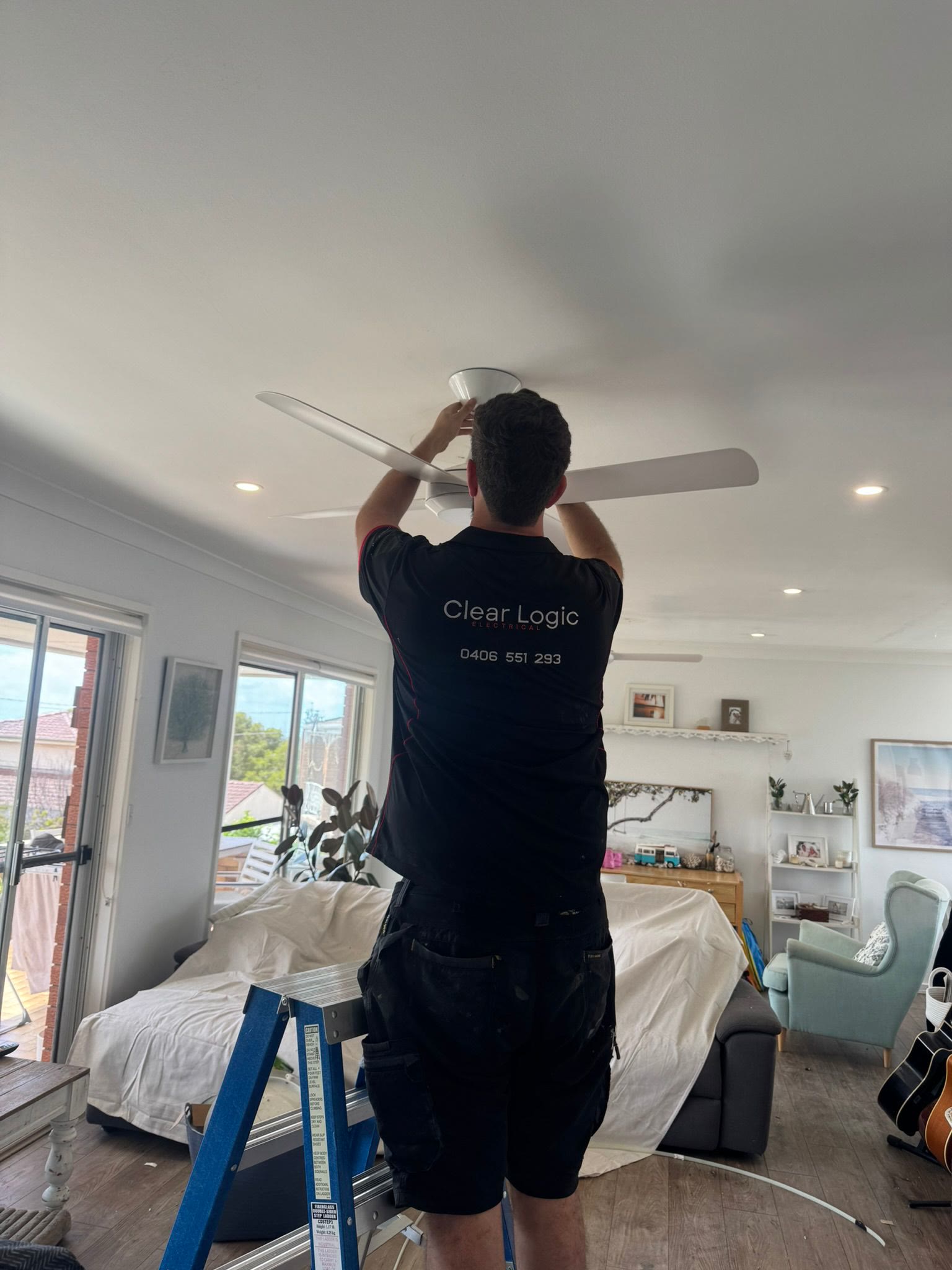 Clear Logic electrician installing a ceiling fan on site
